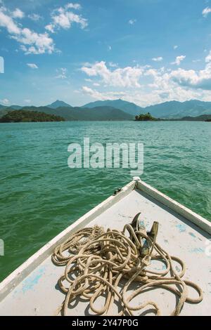 Paraty, Brazil. Fishing boat sailing in the bay of Paraty. Bow detail with old rope and anchor. In the background the Bocaina Mountains. Stock Photo