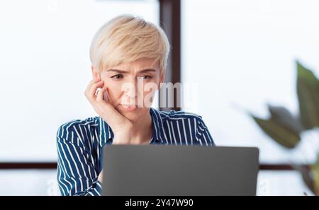 Serious Business Woman At Laptop Sitting Touching Chin In Office Stock Photo