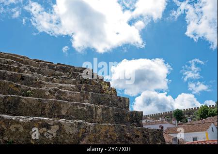 Ancient stone steps leading up to the medieval walls of Óbidos under a bright blue sky Stock Photo