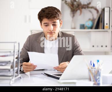 Male bookkeeper doing paperwork in workplace in office - checks accounting documents Stock Photo
