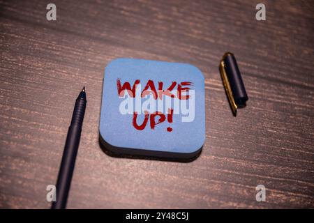 WAKE UP text on a sticky with coffee and pen on wooden background Stock Photo
