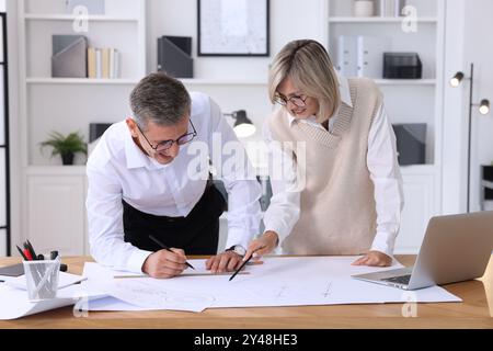 Architects making engineering drawing at wooden table in office Stock Photo