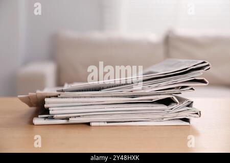 Stack of newspapers in different languages on table indoors Stock Photo