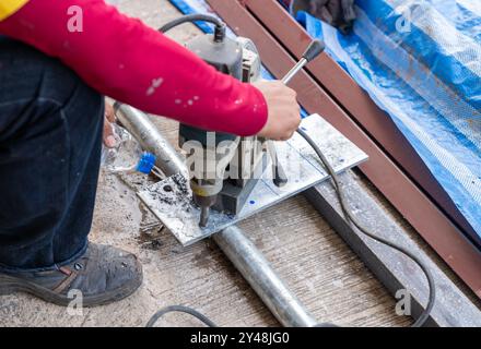 Worker use magnetic drill drilling metal plate in workshop. Stock Photo