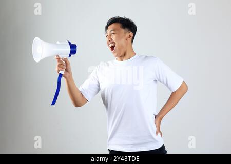 Asian Indonesian  Young Man in White T shirt Shouting Using Megaphone, Isolated on White Stock Photo