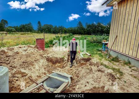 Construction of sewerage system for country house, installation of septic tank made of concrete rings. Stock Photo