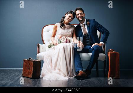 Groom, bride and portrait on couch for wedding, relationship and love with holding hands or flowers. Couple, happy and people on sofa for marriage Stock Photo
