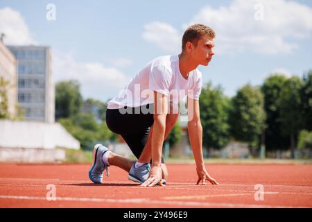 Young male athlete in starting position on a running track outdoors. Stock Photo