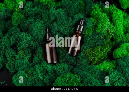 Brown glass dropper bottles arranged on green moss in a natural setting Stock Photo