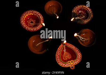 Hindu festival of lights. Top view of Diwali oil lamps lit during on black background. Stock Photo