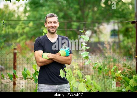 Portrait of smiling gardener posing standing in his garden at summer Stock Photo