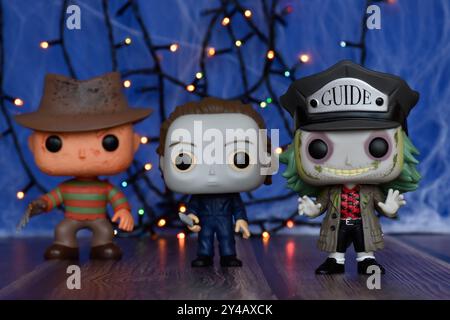 Funko Pop action figures of horror characters Freddy Krueger, Michael Myers and Beetlejuice. Blue fog, spider web, colorful lights, Halloween vibes. Stock Photo