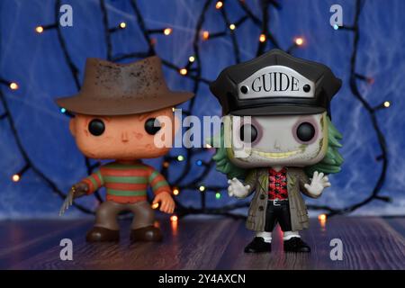 Funko Pop action figures of popular horror characters Freddy Krueger and Beetlejuice. Blue fog, spider web, colorful lights, spooky Halloween vibes. Stock Photo