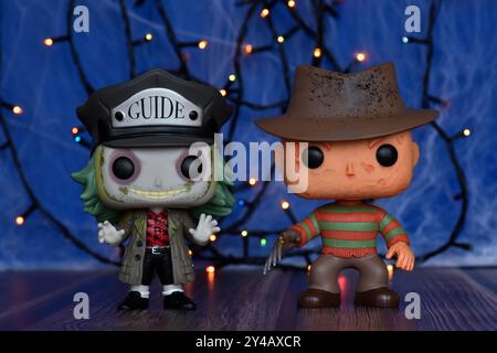 Funko Pop action figures of popular horror characters Freddy Krueger and Beetlejuice. Blue fog, spider web, colorful lights, spooky Halloween vibes. Stock Photo