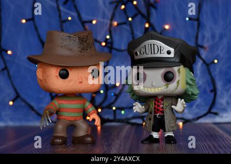 Funko Pop action figures of popular horror characters Freddy Krueger and Beetlejuice. Blue fog, spider web, colorful lights, spooky Halloween vibes. Stock Photo