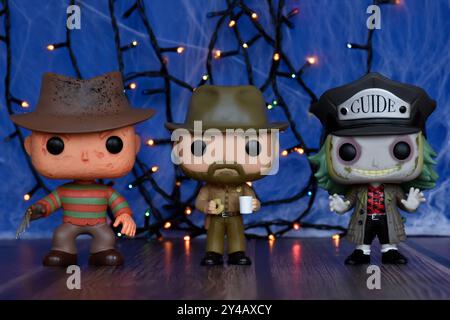 Funko Pop action figures of horror characters Freddy Krueger, Jim Hopper and Beetlejuice. Blue fog, spider web, colorful lights, Halloween vibes. Stock Photo