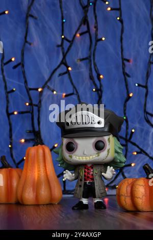 Funko Pop action figure of Beetlejuice from Tim Burton comedy horror film. Blue foggy background, colorful lights, Halloween pumpkins, spider web. Stock Photo