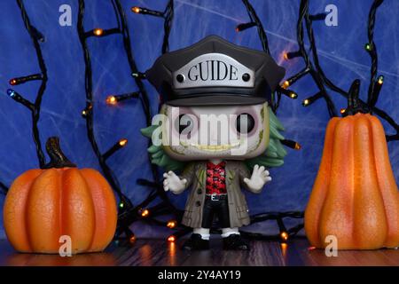 Funko Pop action figure of Beetlejuice from Tim Burton comedy horror film. Blue foggy background, colorful lights, Halloween pumpkins, spider web. Stock Photo