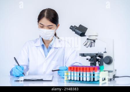 Woman working in a laboratory, blood test and team of scientists in lab working on medical experiment. Stock Photo