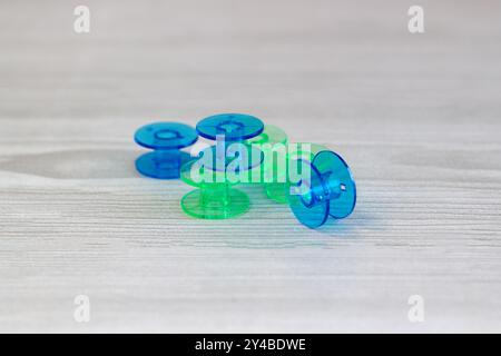 Bright colored plastic bobbins for a sewing machine on a light wooden background close up, selected art focus front view Stock Photo