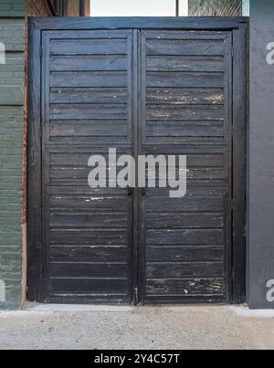Antique wooden doors closing alleyway between two brick buildings. Stock Photo
