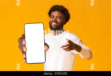 Cheerful black man greeting happily, indicating to camera Stock Photo