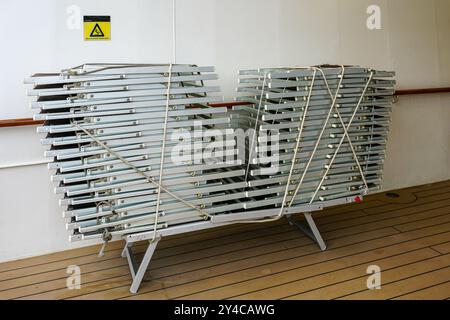 Sun loungers folded, stacked and secured with rope on a board deck of a cruise ship, a lot of empty sunbeds, sun loungers near the pool, sunbeds stack Stock Photo