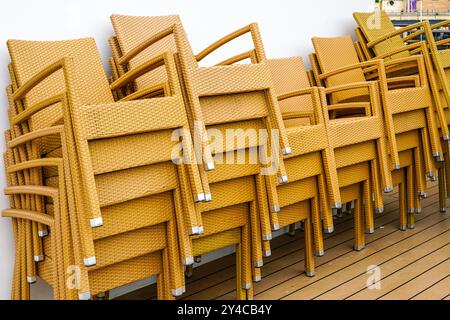 Stack of yellow braided plastic relax chairs with metal legs on cruise ship board deck, plaited chairs for home, garden, balcony, indoor, outdoor use Stock Photo