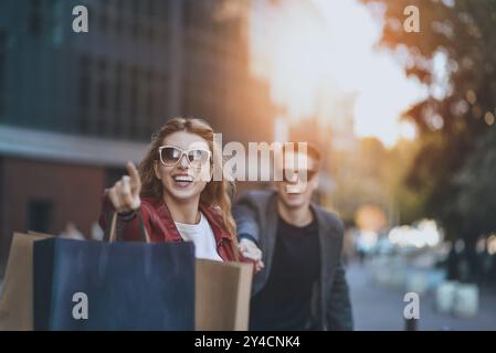 Couple in shopping together. Young couple holding hands and running through street Stock Photo