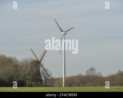 Windmill next to a wind turbine in a field with trees in the background, wuellen, muensterland, detuschland Stock Photo