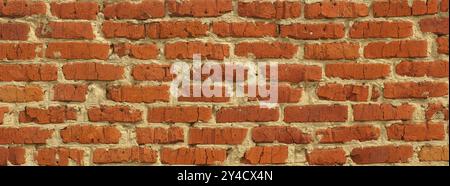 Panoramic background of an old scratched red brick wall. Close up. Stock Photo