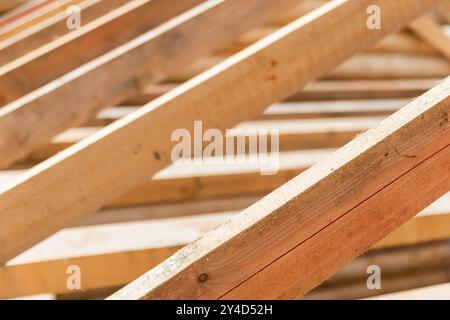 Wooden house roof is under construction. Rafters and beams are in a row. Background photo with selective soft focus Stock Photo