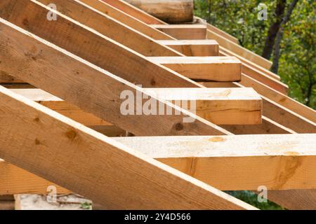 New wooden house roof is under construction. Background photo with rafters and beams in a row with selective soft focus Stock Photo