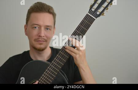 A man playing the guitar. Hands on the strings. Close-up portrait. Chord selection. Musician playing electric guitar. Banner wallpaper with copy space Stock Photo