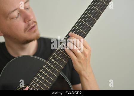 A man playing the guitar. Hands on the strings. Close-up portrait. Chord selection. Musician playing electric guitar. Banner wallpaper with copy space Stock Photo