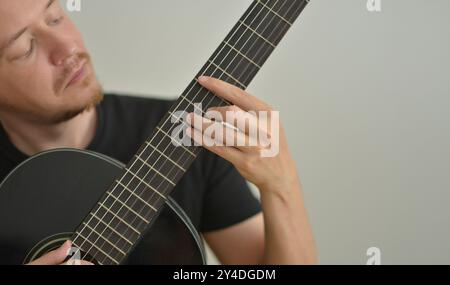A man playing the guitar. Hands on the strings. Close-up portrait. Chord selection. Musician playing electric guitar. Banner wallpaper with copy space Stock Photo