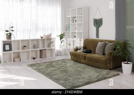 Interior of living room with glucophone on green sofa and shelf units Stock Photo