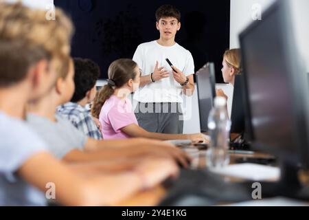 Guy teacher teaches group of students in computer class Stock Photo