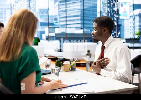 HR department expert ensuring job candidate possesses necessary qualifications fitting for company culture. Headhunter negotiating salary package and other benefits with african american man Stock Photo