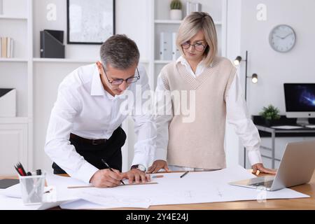 Architects making engineering drawing at wooden table in office Stock Photo