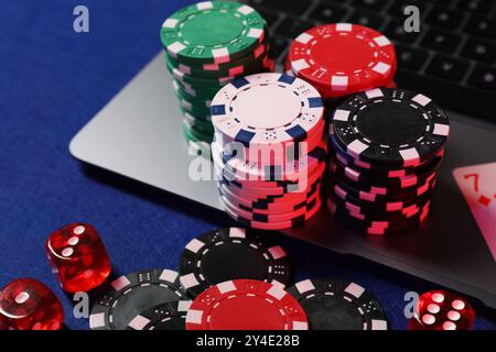 Poker chips, laptop and dices on blue table. Online game Stock Photo