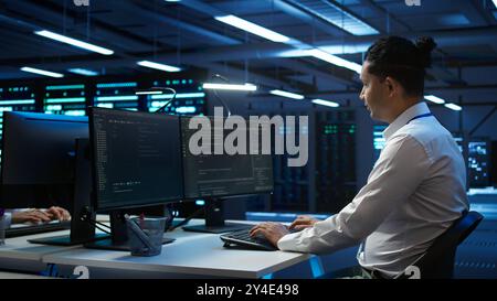Portrait of upbeat admin in data center managing servers, operating systems and software programs. Joyous specialist in server hub ensuring networks are secure and functioning properly, camera B Stock Photo