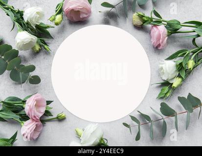 A creative setup features pink and white flowers beautifully placed around a blank circle on a gray surface, ideal for invitations or decorative purpo Stock Photo