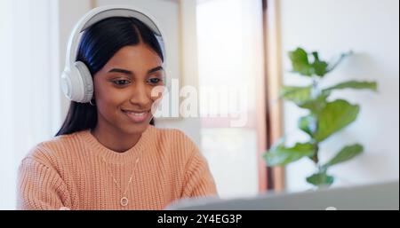 Indian woman, remote work and laptop with headphones for listening, hearing and editing online audio. Freelancer, female person or video editor with Stock Photo