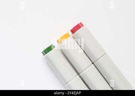 close up of three closed markers lying on white page of sketch book Stock Photo