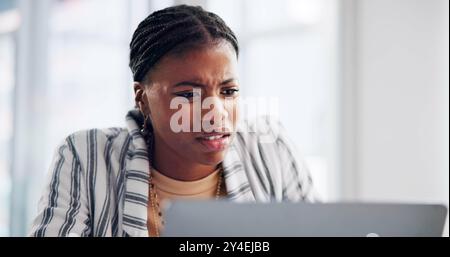 Frustrated, black woman and confused with laptop for bad news, mistake or review at office. Young African, female person or annoyed employee with Stock Photo