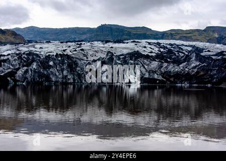 Solheimajokull glacier covered in soot from previous eruptions with the glacial lake descending from the volcano near Vik in Iceland Stock Photo