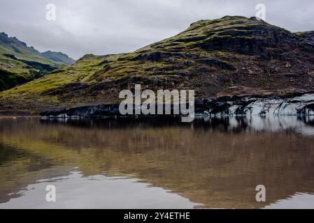 Solheimajokull glacier covered in soot from previous eruptions with the glacial lake descending from the volcano near Vik in Iceland Stock Photo