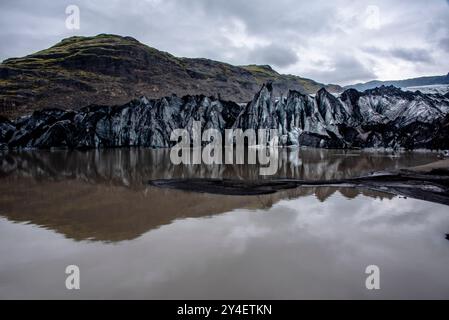 Solheimajokull glacier covered in soot from previous eruptions with the glacial lake descending from the volcano near Vik in Iceland Stock Photo