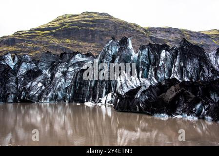 Solheimajokull glacier covered in soot from previous eruptions with the glacial lake descending from the volcano near Vik in Iceland Stock Photo